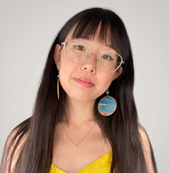 Valentina Wang guarda l'obiettivo con un mezzo sorriso: occhiali dalla montatura sottile, capelli lunghi e un orecchino tondo azzurro.